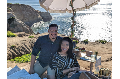 a couple sitting on a rock near the ocean