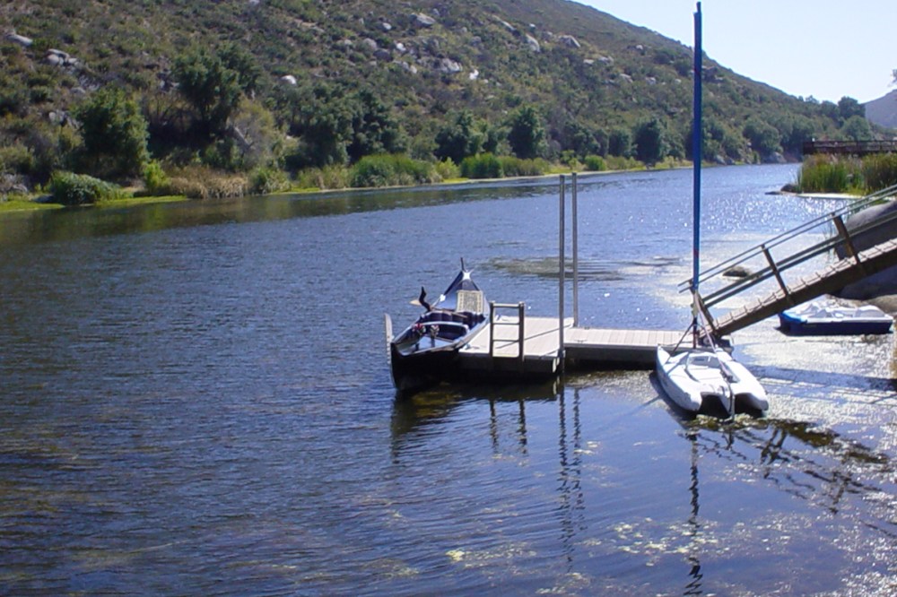 Venetian-style gondola for rent docked at a peaceful private lakeside pier surrounded by scenic hills in San Diego.