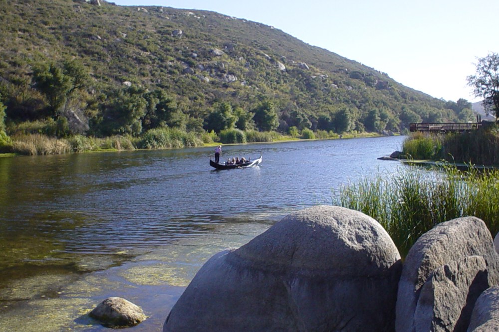 Gondola for rent gliding across a peaceful private lake surrounded by scenic hills and greenery in San Diego.