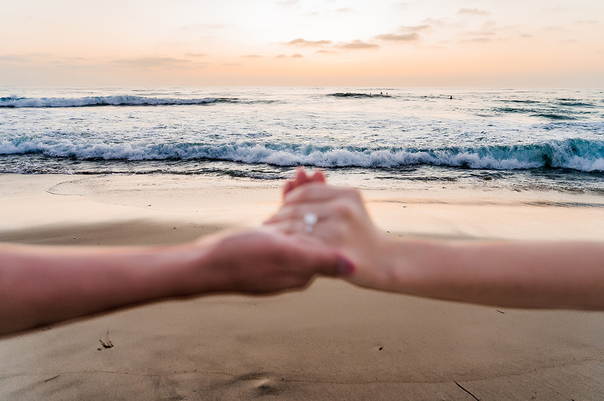 Couple holding hands by the ocean during a San Diego honeymoon