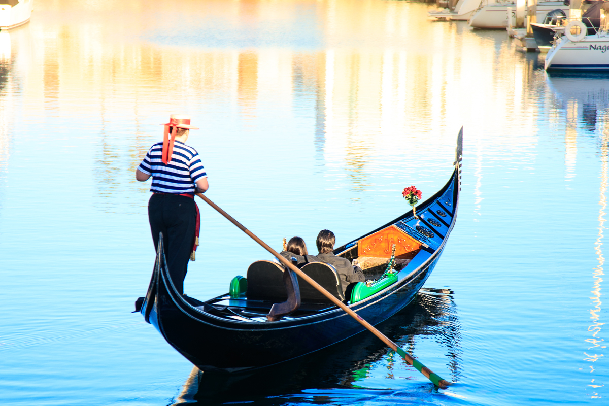 Gondola cruising through the Coronado Cays at dusk with waterfront homes and lights