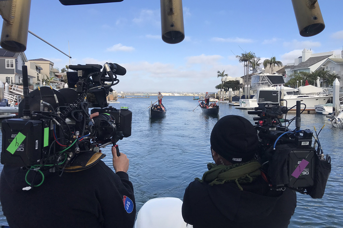 Two videographers filming two gondolas from a motorboat in Southern California