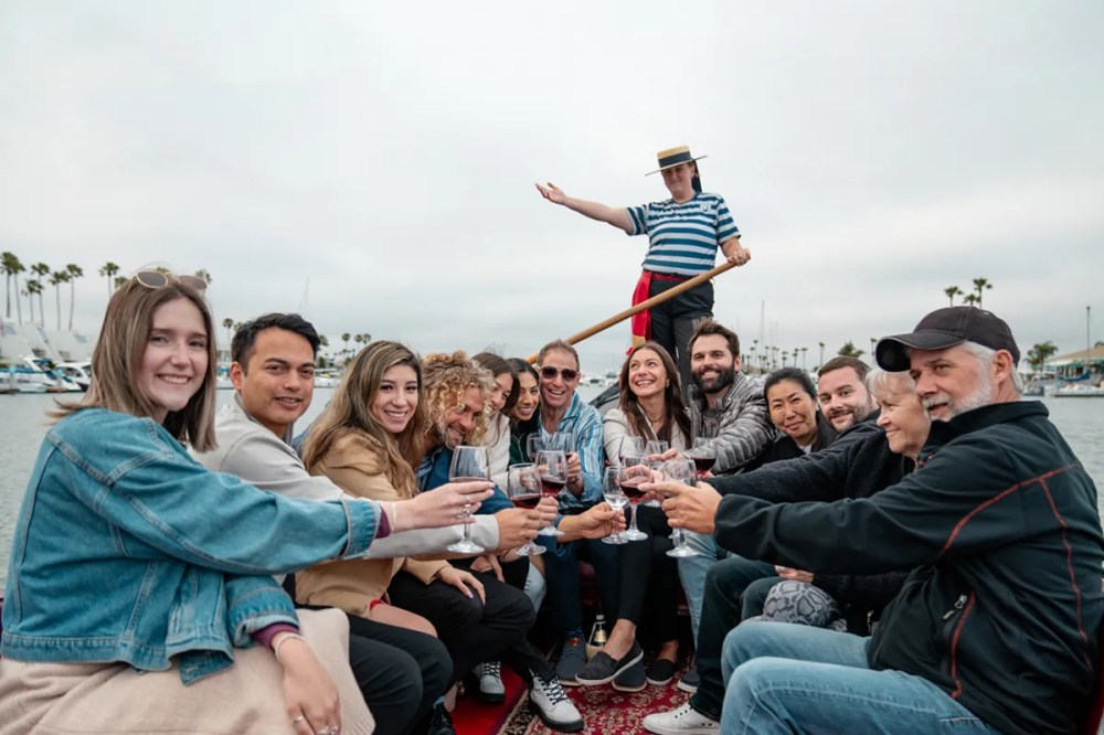 Group of friends raising wine glasses in a toast during a private gondola cruise in San Diego.